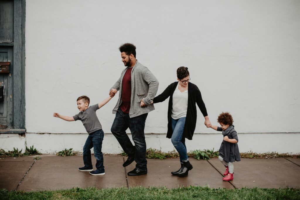 pexels-photo-2253879-2253879 A joyful family walking together outdoors, holding hands in a playful and happy moment.